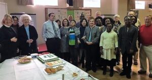 A group of people standing around a table with food.