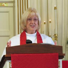 A woman in white and red is speaking at the podium