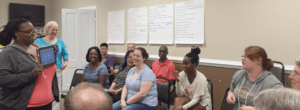 A group of people sitting in front of large white boards.