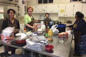 A group of people in the kitchen preparing food.