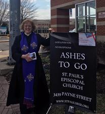 A woman in a blue robe standing next to a sign.