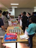 A group of people standing around tables with cans.