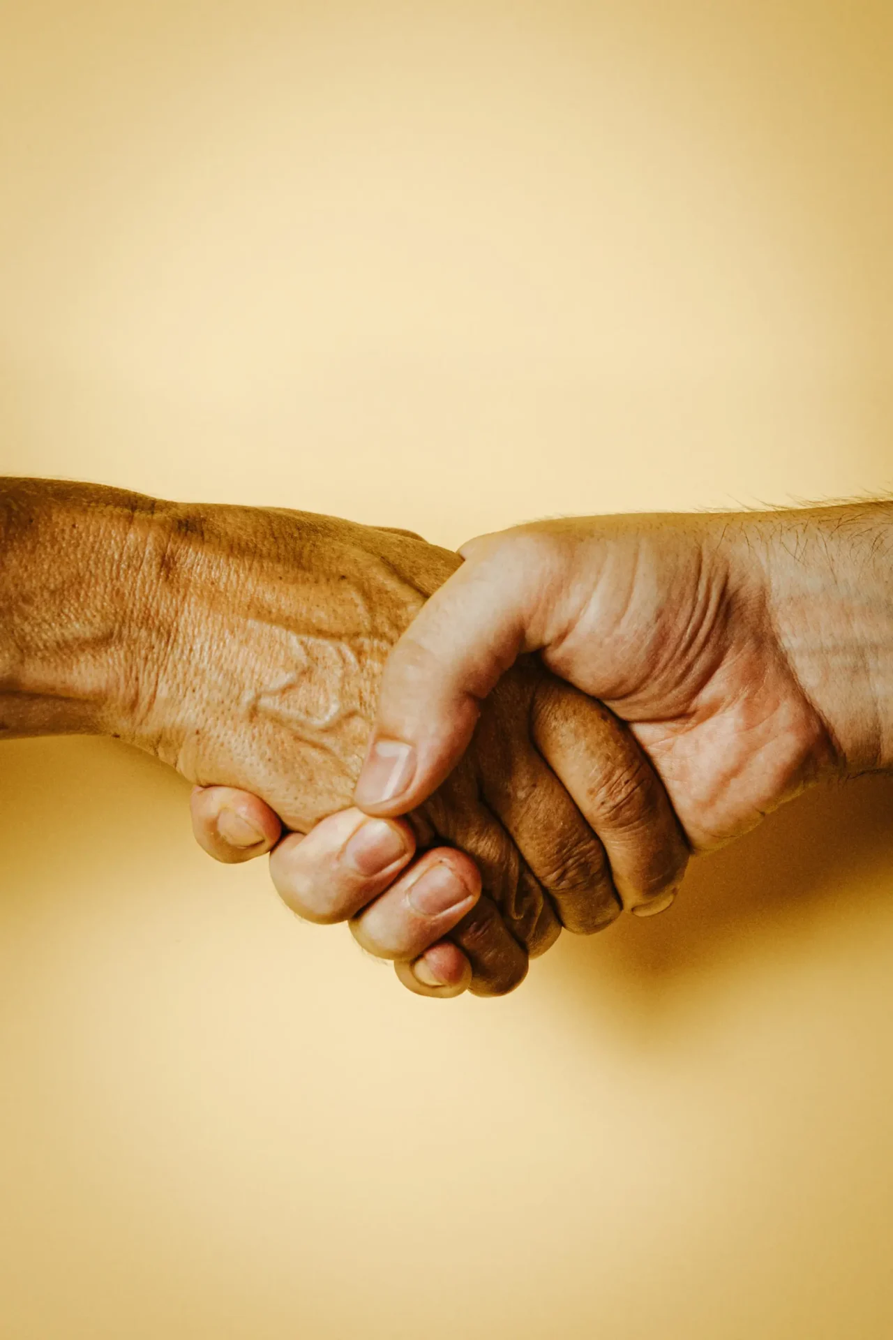 Two people shaking hands over a yellow background.